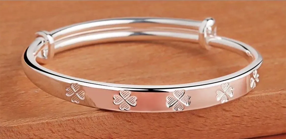 Silver bracelet with floral patterns on a wooden surface