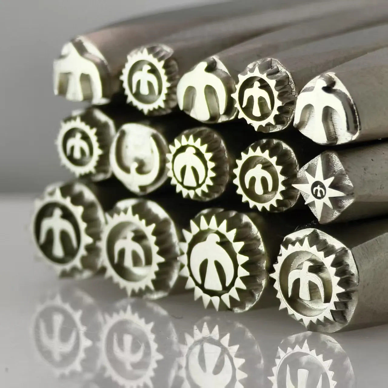 Set of metal stamps with various designs on a reflective surface
