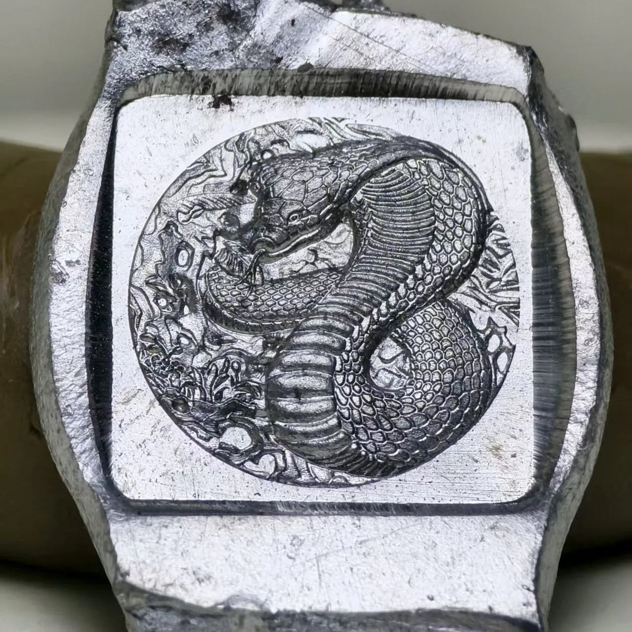 Close-up of a stone with a engraved design of a snake and flower pattern.