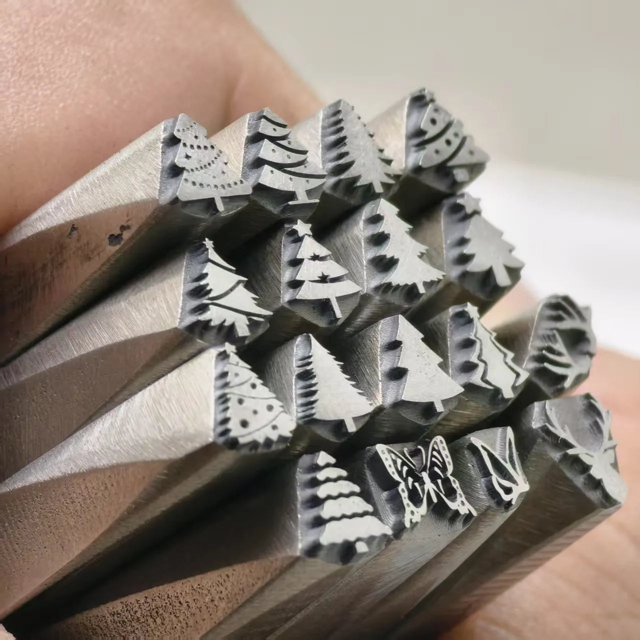 Set of metal stamps with various shapes held by a person